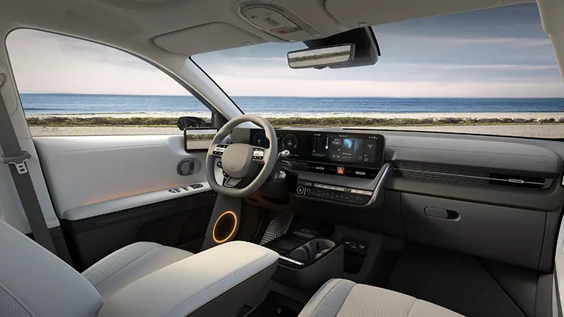 IONIQ 5 interior from driver's seat showing dual 12.3-inch displays and orange-accented center console