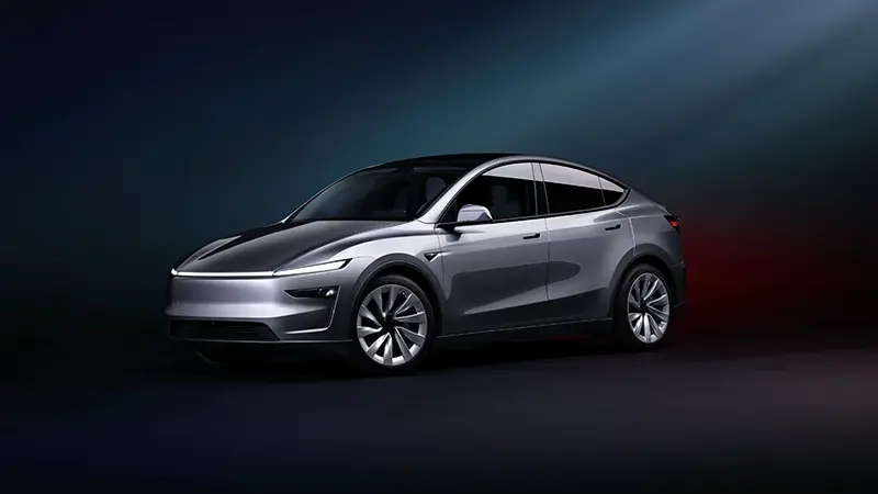 Tesla Model Y Premium in silver captured at three-quarter angle, showcasing its continuous LED light bar and flush door handles in a futuristic design language